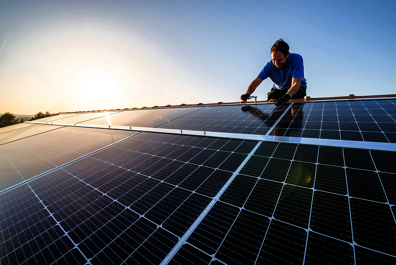 Mann auf Dach mit Qcells Solaranlage 