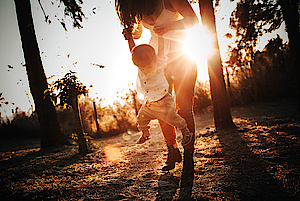 Mutter und Kind spielen im Wald bei Sonnenschein 