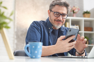 Mann ueberprueft Qcells App am Handy 